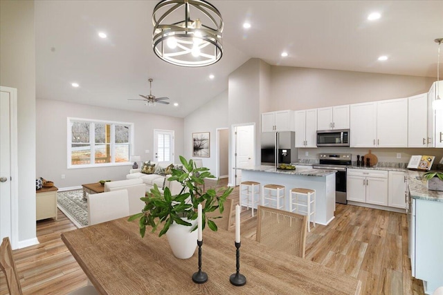 dining space with recessed lighting, light wood-style floors, ceiling fan, high vaulted ceiling, and baseboards