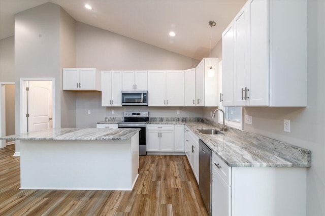 kitchen with white cabinets, appliances with stainless steel finishes, a sink, high vaulted ceiling, and light wood-type flooring