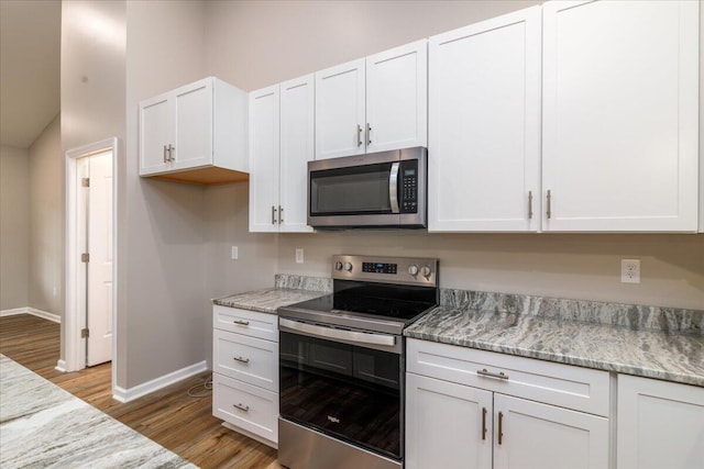 kitchen featuring stainless steel appliances, light wood-type flooring, white cabinetry, and light stone countertops