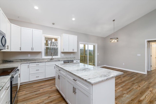 kitchen featuring black range with electric stovetop, white cabinets, a kitchen island, vaulted ceiling, and a sink