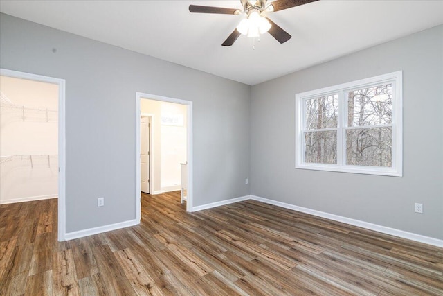 unfurnished bedroom with ceiling fan, wood finished floors, baseboards, a spacious closet, and a closet