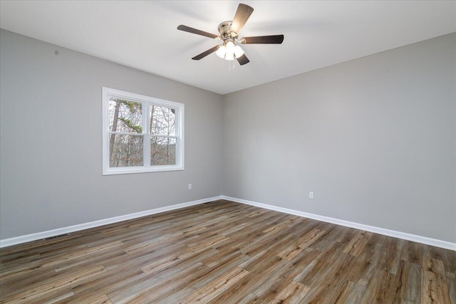 empty room with ceiling fan, wood finished floors, and baseboards