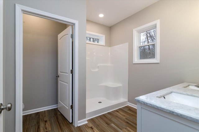 bathroom with toilet, wood finished floors, vanity, baseboards, and walk in shower