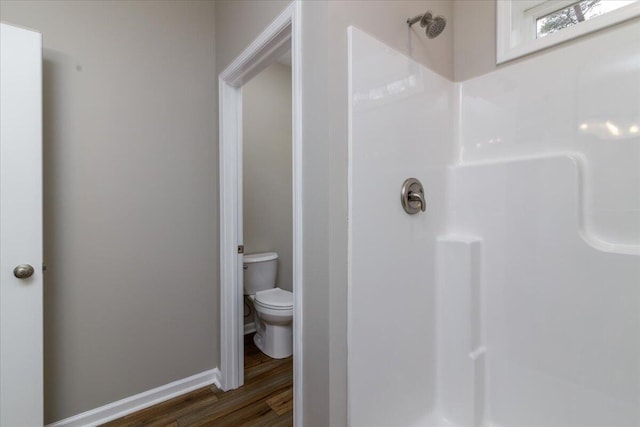 bathroom featuring toilet, baseboards, a shower stall, and wood finished floors