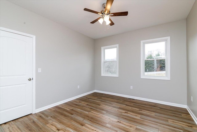 empty room featuring ceiling fan, baseboards, and wood finished floors