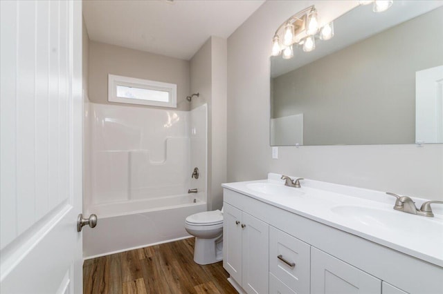 bathroom featuring shower / bathtub combination, wood finished floors, a sink, and toilet