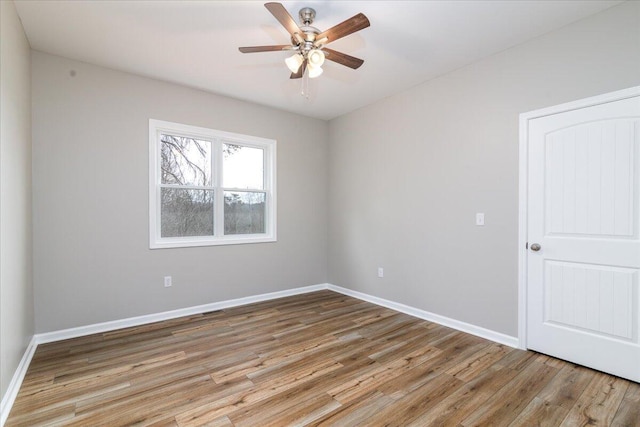 empty room featuring light wood finished floors, baseboards, and a ceiling fan