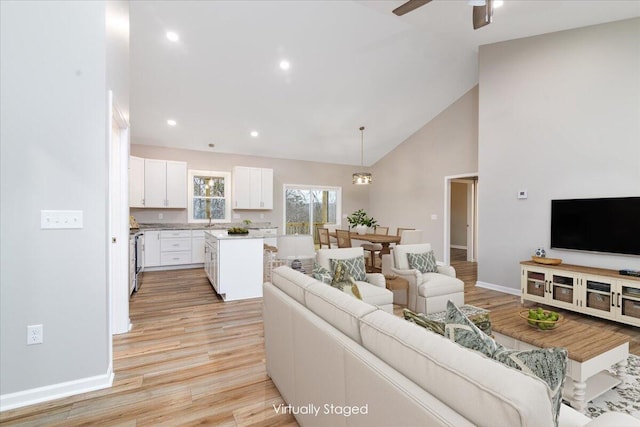 living area with baseboards, ceiling fan, light wood-style floors, high vaulted ceiling, and recessed lighting