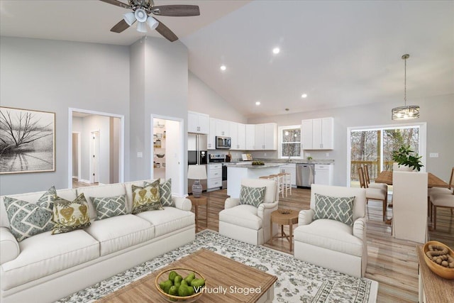 living area with high vaulted ceiling, recessed lighting, light wood finished floors, and a ceiling fan