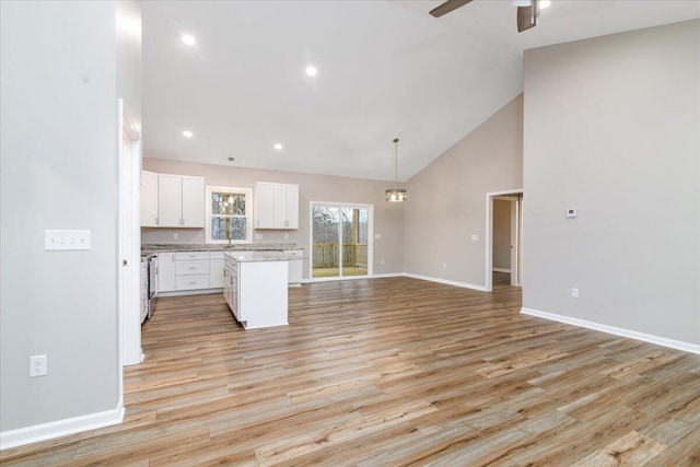 kitchen with white cabinets, ceiling fan, a center island, baseboards, and light wood-type flooring