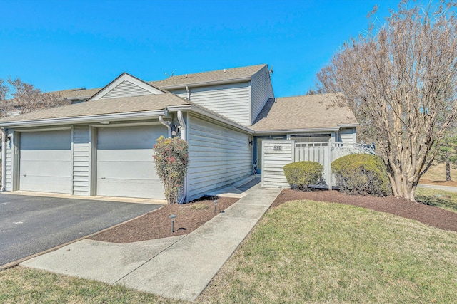 view of front of property with a garage, driveway, a front lawn, and a shingled roof