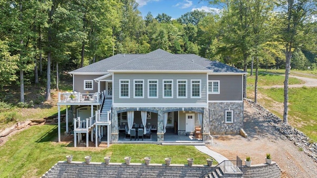 rear view of property featuring stairs, stone siding, a yard, dirt driveway, and a patio area