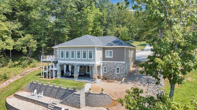 rear view of house with stone siding and a patio