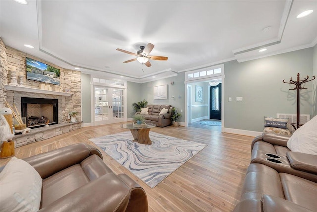 living area with ceiling fan, light wood-style flooring, a fireplace, baseboards, and ornamental molding