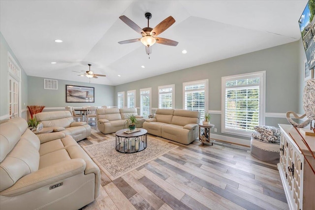 living room with lofted ceiling, light wood-style floors, visible vents, and a wealth of natural light