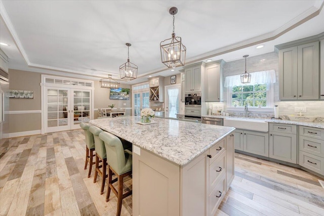 kitchen featuring a sink, a kitchen island, a kitchen bar, a raised ceiling, and pendant lighting