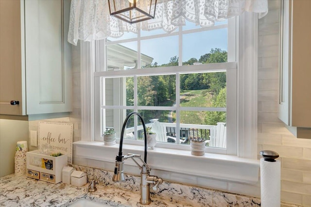 interior details featuring light stone counters, white cabinets, and a sink