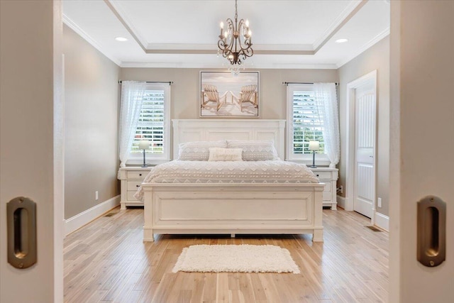 bedroom featuring an inviting chandelier, a raised ceiling, and light wood-style floors