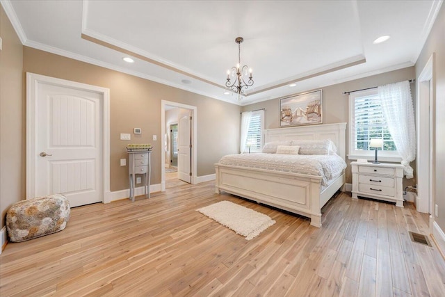 bedroom with light wood finished floors, a tray ceiling, ornamental molding, and visible vents