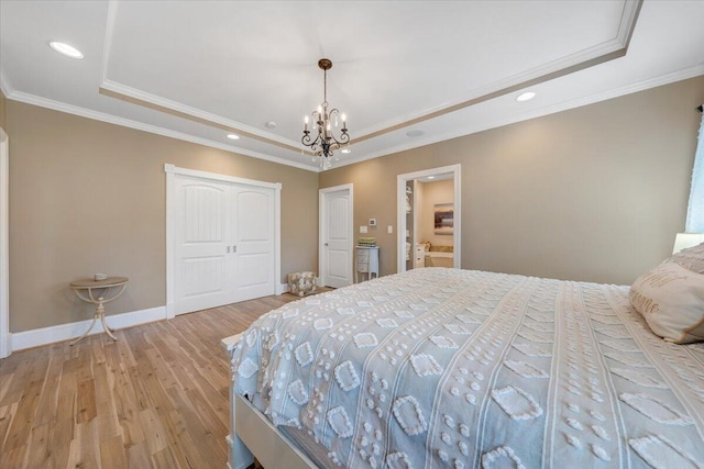 bedroom with light wood-style floors, a tray ceiling, a closet, and baseboards