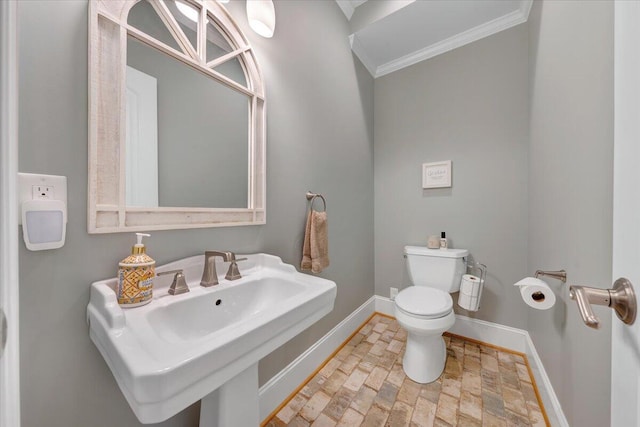 half bathroom featuring crown molding, toilet, a sink, and baseboards