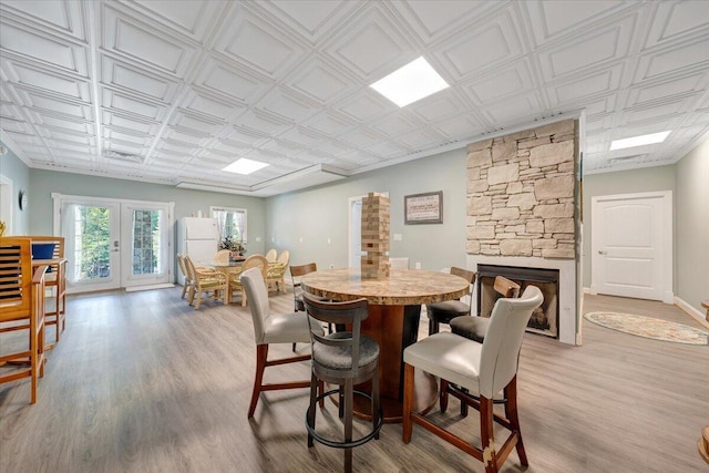 dining room featuring an ornate ceiling, french doors, a fireplace, and wood finished floors