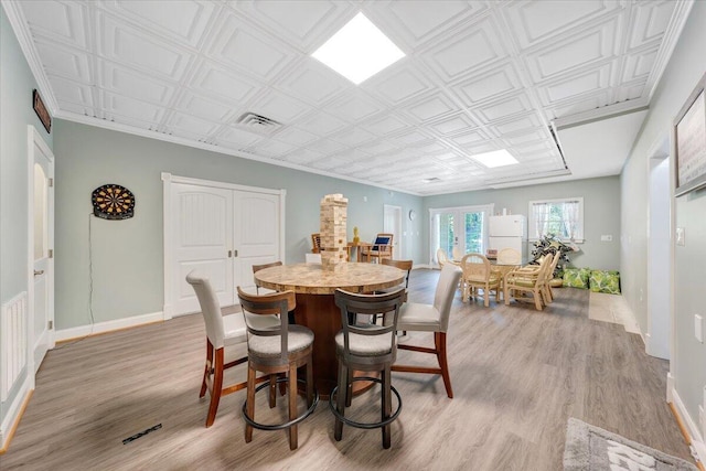 dining room with french doors, light wood finished floors, an ornate ceiling, and baseboards