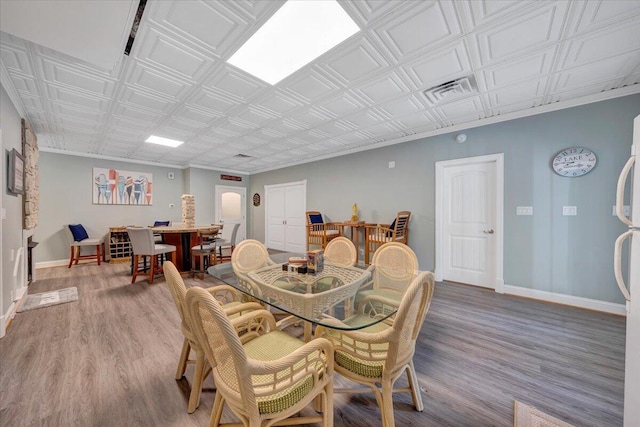 dining area with wood finished floors, an ornate ceiling, and baseboards