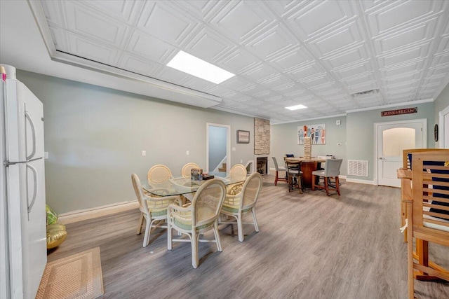 dining space with stairs, visible vents, baseboards, and wood finished floors