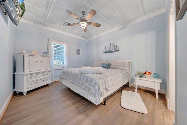 bedroom with an ornate ceiling, baseboards, light wood-style flooring, and ornamental molding