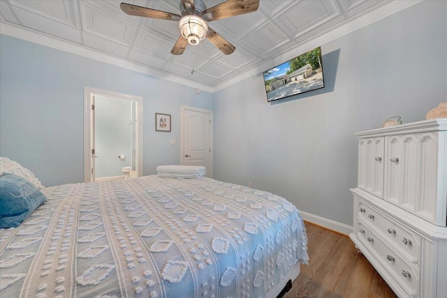 bedroom featuring an ornate ceiling, crown molding, connected bathroom, wood finished floors, and baseboards