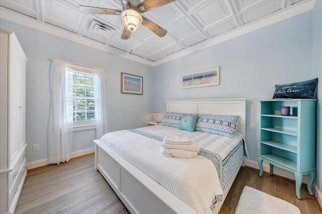 bedroom with visible vents, baseboards, a ceiling fan, an ornate ceiling, and wood finished floors