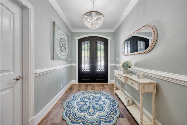 foyer entrance featuring arched walkways, french doors, crown molding, and an inviting chandelier