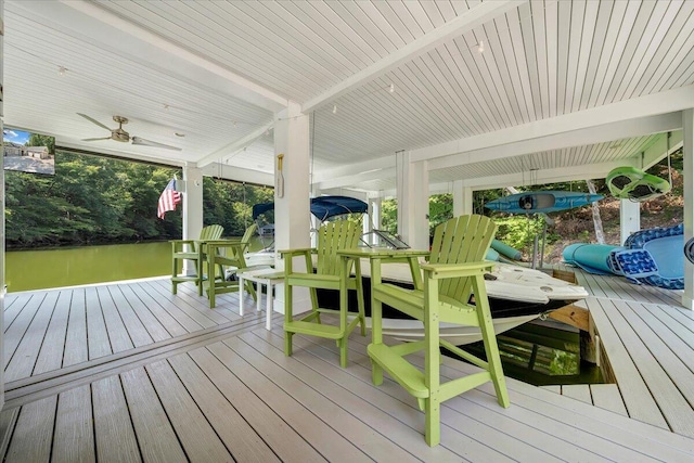 wooden deck with a ceiling fan, a water view, a boat dock, and boat lift