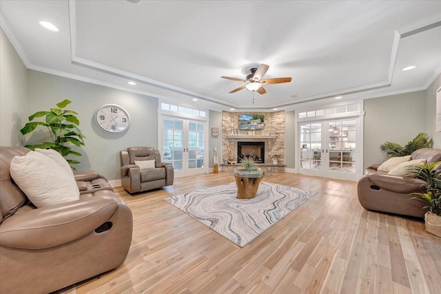 living room with light wood-type flooring, french doors, a fireplace, and a raised ceiling