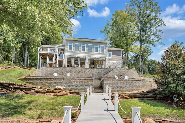 rear view of house with stone siding, stairs, and a lawn