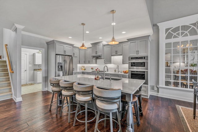 kitchen with dark wood-style flooring, stainless steel appliances, gray cabinetry, ornamental molding, and a sink