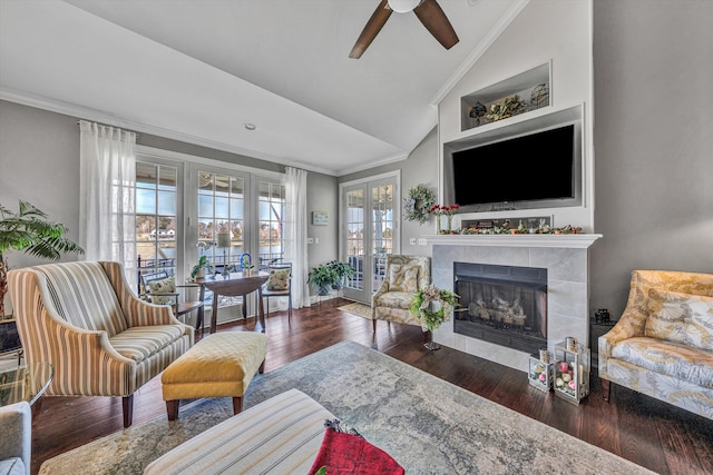 living room with lofted ceiling, a tiled fireplace, hardwood / wood-style flooring, and crown molding