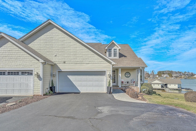 view of front facade with a garage, driveway, a shingled roof, and a porch