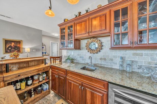 kitchen featuring light stone counters, wine cooler, a sink, visible vents, and backsplash