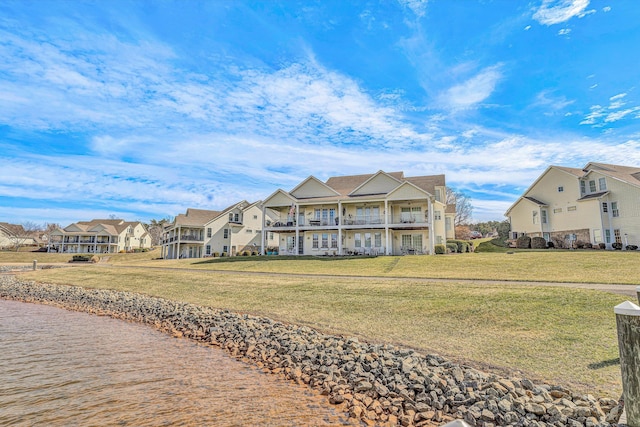 view of front of property featuring a front yard, a balcony, and a residential view