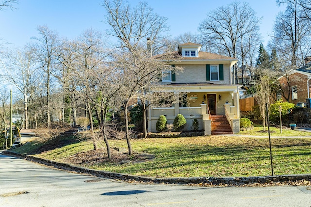 american foursquare style home featuring a porch and a front yard