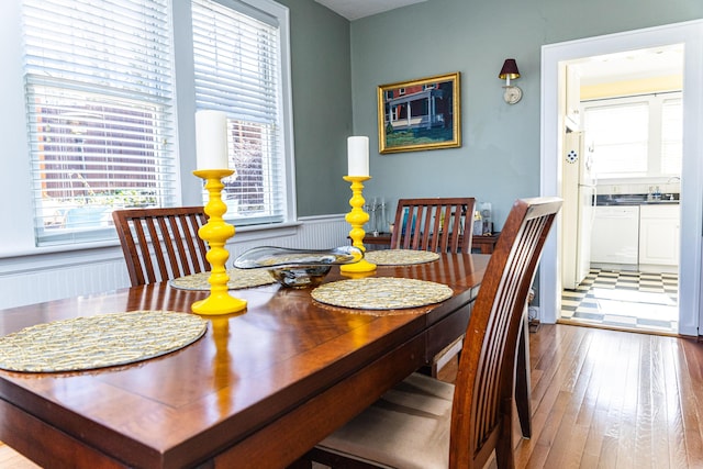 dining space with hardwood / wood-style floors and wainscoting