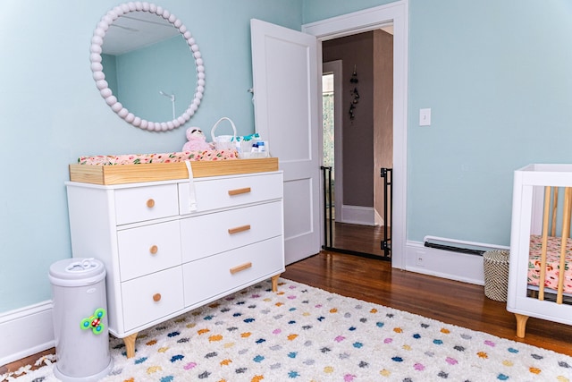 bedroom featuring a crib, baseboards, and wood finished floors