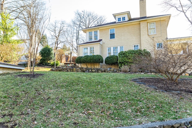 exterior space featuring brick siding, a lawn, and a chimney