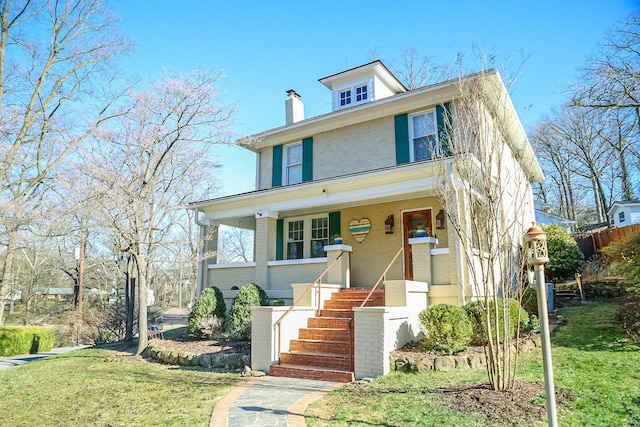 traditional style home featuring covered porch, brick siding, stairway, and a front yard