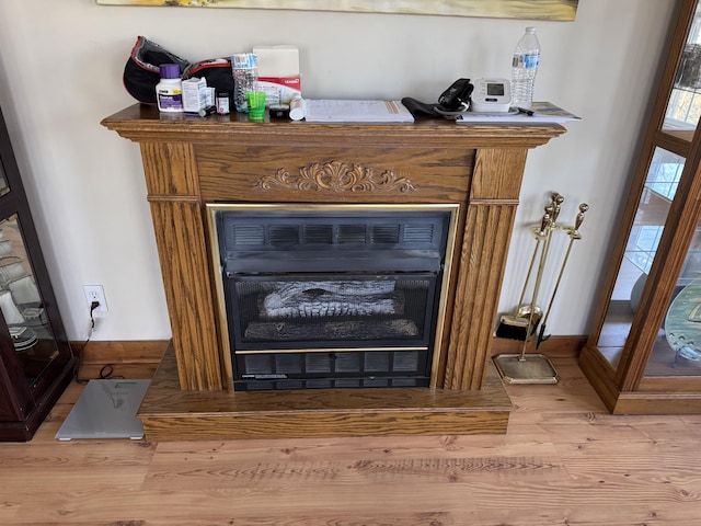 interior details featuring a fireplace, wood finished floors, and baseboards