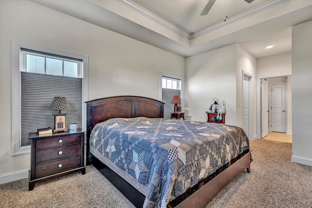 carpeted bedroom featuring a ceiling fan, baseboards, a raised ceiling, and crown molding