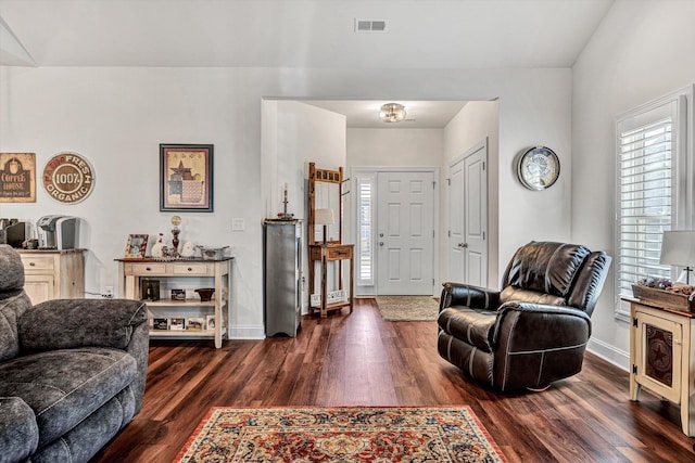 living room with dark wood-type flooring, visible vents, and baseboards