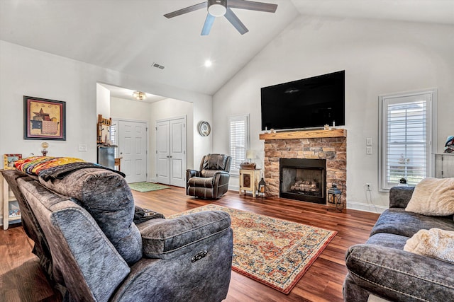 living area with visible vents, a ceiling fan, wood finished floors, a fireplace, and high vaulted ceiling